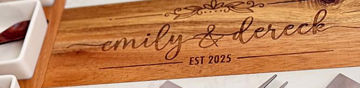 Set of personalized cheese knives with wooden handles on a cutting board engraved with 'emily & dereck EST 2025'.
