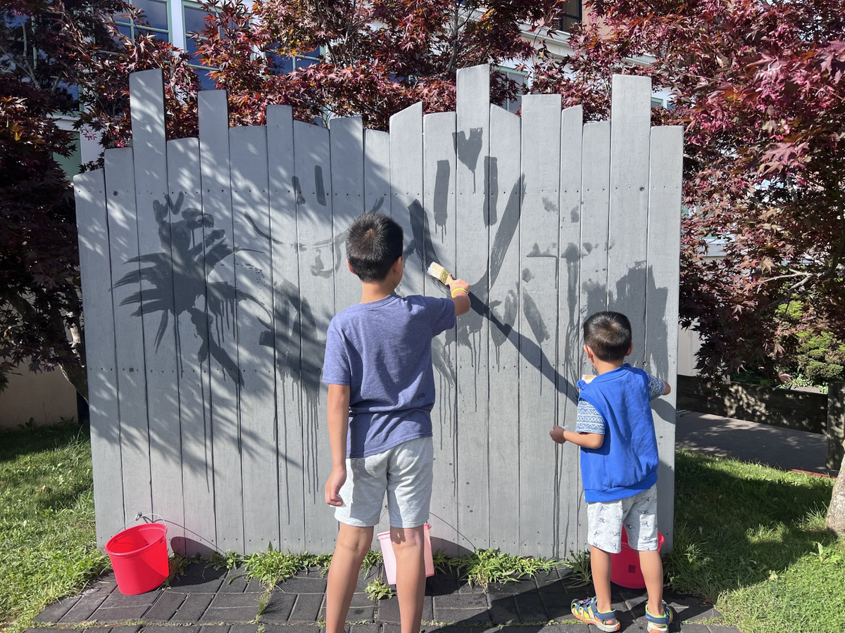 June’s two sons painting together outdoors, photographed from behind.